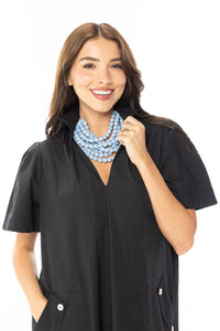 A woman modeling a black dress with pockets on a white background