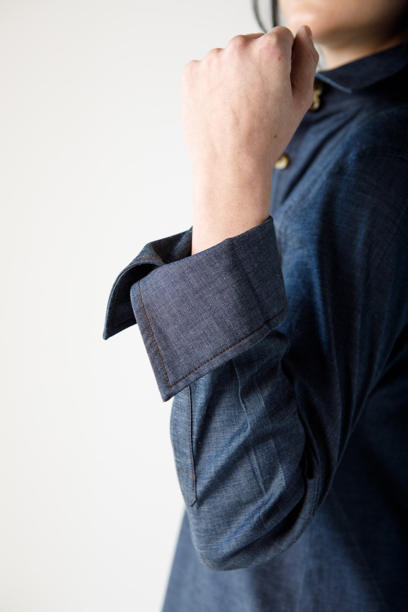 Woman wearing a blue top with rolled up sleeves on a white background