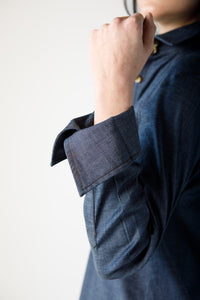 Woman wearing a blue top with rolled up sleeves on a white background