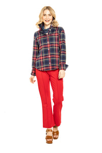 Woman wearing red pants with chunky heel and plaid blouse against a white background