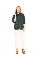 Woman wearing a green plaid shirt and white pants on a white background