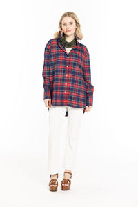 Woman wearing a red and blue plaid shirt with white pants on a white background