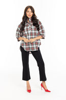 Woman wearing black pants and a plaid top with red heels against a white background