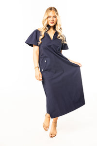 Woman wearing a navy blue dress with short sleeves and nude heels on a white background