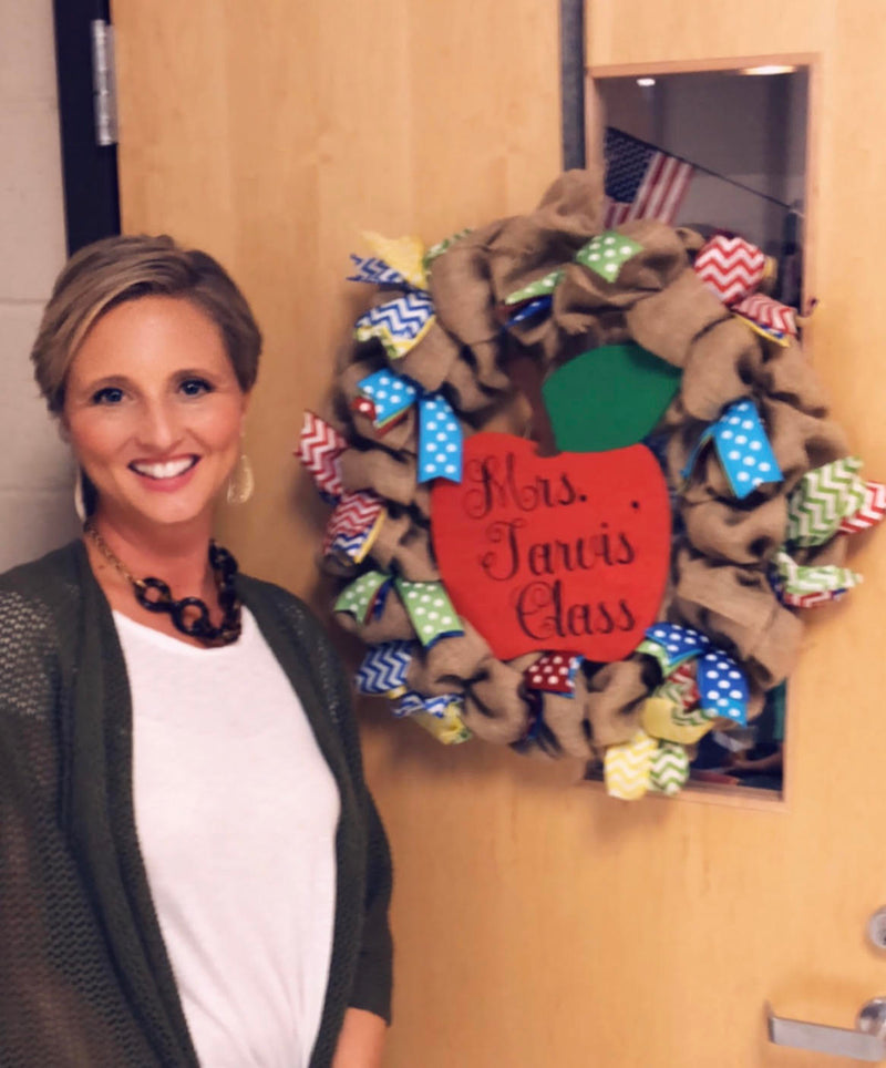 Holly standing next to a decorative wreath with 'Mrs. Jarvis Class' text on a door.